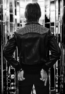 Per facing a mirrored alcove with his back to the camera.