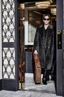 Per in a fur coat stepping out of an elevator.