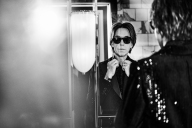 Per in an all-black outfit checking himself in the mirror.